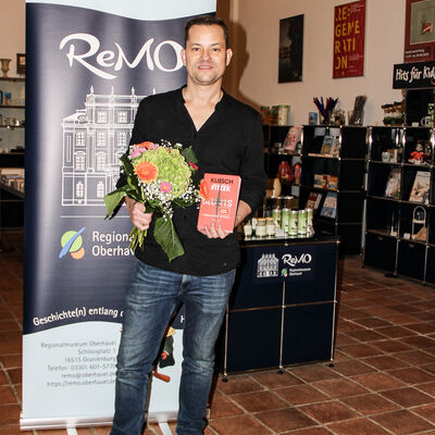 Vincent Kliesch mit dem Buch "Auris" und einem Blumenstrauß in den  Händen.